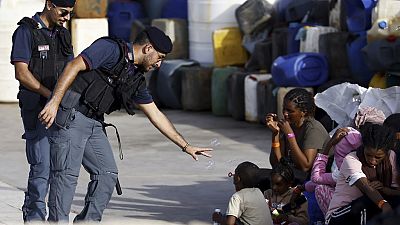 A police officer plays with a migrant child blowing soap bubbles in the port of the Sicilian island of Lampedusa, southern Italy, Monday, Sept. 18, 2023.