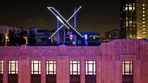 Workers install lighting on an "X" sign atop the company headquarters, formerly known as Twitter, in downtown San Francisco