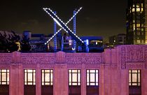 Workers install lighting on an "X" sign atop the company headquarters, formerly known as Twitter, in downtown San Francisco