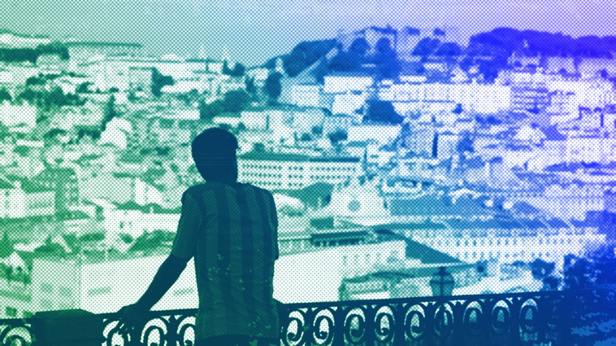 A young man takes looks from a viewpoint overlooking downtown Lisbon, August 2022