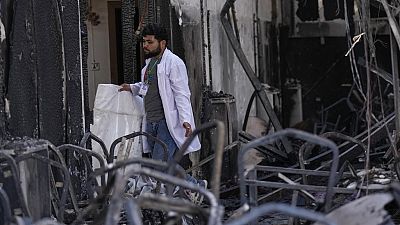 A health worker collects the remains of victims at the site of a fatal fire, in the district of Hamdaniya, Nineveh province, Iraq, Thursday, Sept. 28, 2023. 
