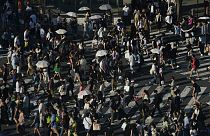People carry umbrellas to shield themselves from the sun as they walk across an intersection Monday, July 17, 2023, in Tokyo. 