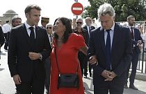 French President Emmanuel Macron walks with leader of the French communist party Fabien Roussel, right, and Isaline Amalric, center.