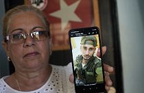 Мать кубинца показывает фото сына в российской военной форме