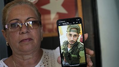 Мать кубинца показывает фото сына в российской военной форме