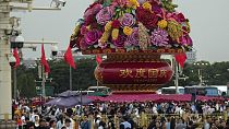 Visitors gather near a giant flower basket on display at the crowded Tiananmen Square to celebrate the 74th anniversary of the founding of the People's Republic of China,.