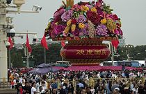 Visitors gather near a giant flower basket on display at the crowded Tiananmen Square to celebrate the 74th anniversary of the founding of the People's Republic of China,.