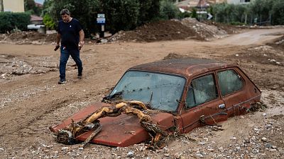 A man walks next to a damaged car after floods in the town of Agria near the city of Volos, Greece, Thursday, 28 September 2023.