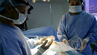 جراح التجميل الدكتور إسياس بيلو يحمل ثديًا من السيليكون أثناء جراحة زراعة الثدي في كاراكاس، فنزويلا، 21 سبتمبر، 2005.