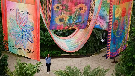 A garden employee poses for a picture near artwork entitled 'House of Spirits' by US artist Jeffrey Gibson, during a photocall for Kew Gardens' 'Queer Nature' 