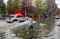Um nova-iorquino, com água pelos joelhos, tenta abrir uma conduta de esgotos, para escoar a água das ruas inundadas, 29 de setembro de 2023