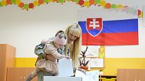 A young girl casts a vote for her mother at a polling station during an early parliamentary election in Bratislava, Slovakia, Saturday, Sept. 30, 2023.