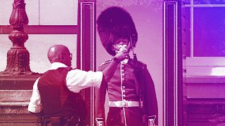  Полицай дава вода на английски боец, носещ обичайната шапка от меча кожа на пост пред Бъкингамския замък, юли 2022 година 