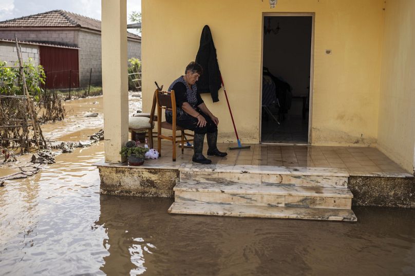 A woman takes a break from cleaning her flooded house in Sotirio village near the city of Volos, Greece, on Friday, 29 September, 2023