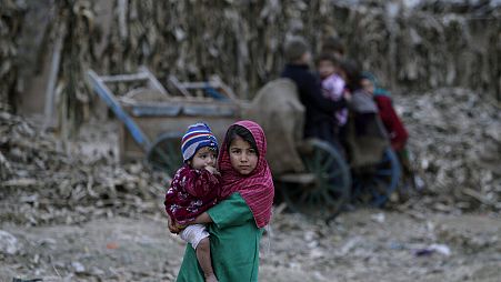 Pakistan'ın başkenti İslamabad'ın dışında yer alan bir mülteci kampında kardeşini kucaklayan bir Afgan göçmen kız çocuğu