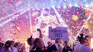 DATEI - Ein Anhänger der rechtsextremen polnischen Partei Konföderation hält ein Wahlkampfplakat eines Kandidaten in Kattowitz hoch, 23. September 2023.