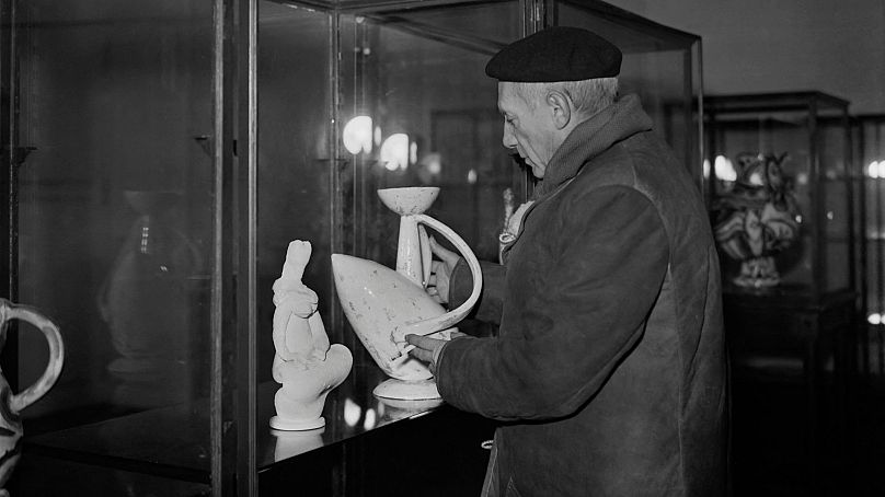 Pablo Picasso looks at a pottery during his exhibition at the Maison de la pensée, on 24 November 1948, in Paris.