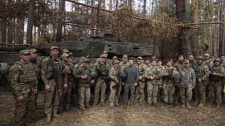 Volodimir Zelenszkij (középen) ukrán katonákkal egy Leopard 2 tank előtt a frontvonalon a harkivi régióban 2023. október 3-án..