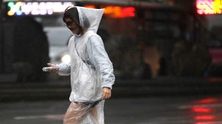 امرأة تمشي في شوارع العاصمة التايوانية تايبيه وتقاوم الأمطار والرياح القوية
