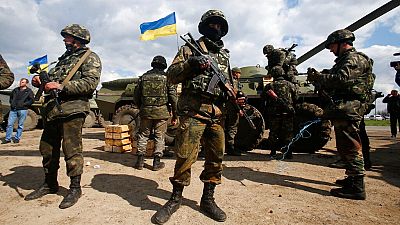FILE - Ukrainian army troops receive ammunition, with a Ukrainian flag in the background, in a field on the outskirts of Izyum, Eastern Ukraine, Tuesday, April 15, 2014.