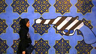 DATEI - Eine iranische Frau geht am Samstag, 2\. November 2013, in Teheran, Iran, an einem gegen die USA gerichteten Wandgemälde vorbei, das an die Wand der ehemaligen US-Botschaft gemalt wurde.