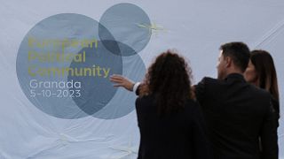 People stand in front of a logo of the European Political Summit, on the eve of the European Political Community summit in Granada,  southern Spain on October 4, 2023. 