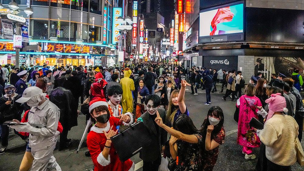 Посетителите на Хелоуин в костюми позират за снимки, докато хиляди