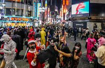 Halloween goers in costumes pose for pictures as thousands gather in Shibuya district in 2021.