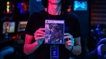 أحد الموظفين يعرض نسخة من لعبة الفيديو التي تم إصدارها حديثًا "Assassin's Creed Mirage"