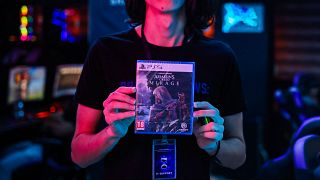 أحد الموظفين يعرض نسخة من لعبة الفيديو التي تم إصدارها حديثًا "Assassin's Creed Mirage"