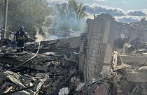 Bombeiros tentam apagar o fogo no local do bombardeamento em Hroza, na Ucrânia