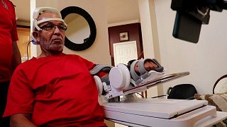  Изображението демонстрира Осуалд ​​Ридус, оживял след удар, изпробващ нова слушалка за четене на мозъка, която може да му помогне да възвърне потреблението на своя крак. 
