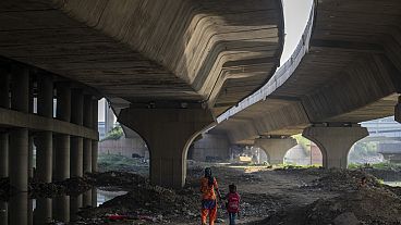 Meera Devi, left, accompanies her daughter Arima, 7, to her school as they walk on the flood plain of Yamuna River, in New Delhi, India, Friday, Sept. 29, 2023. 