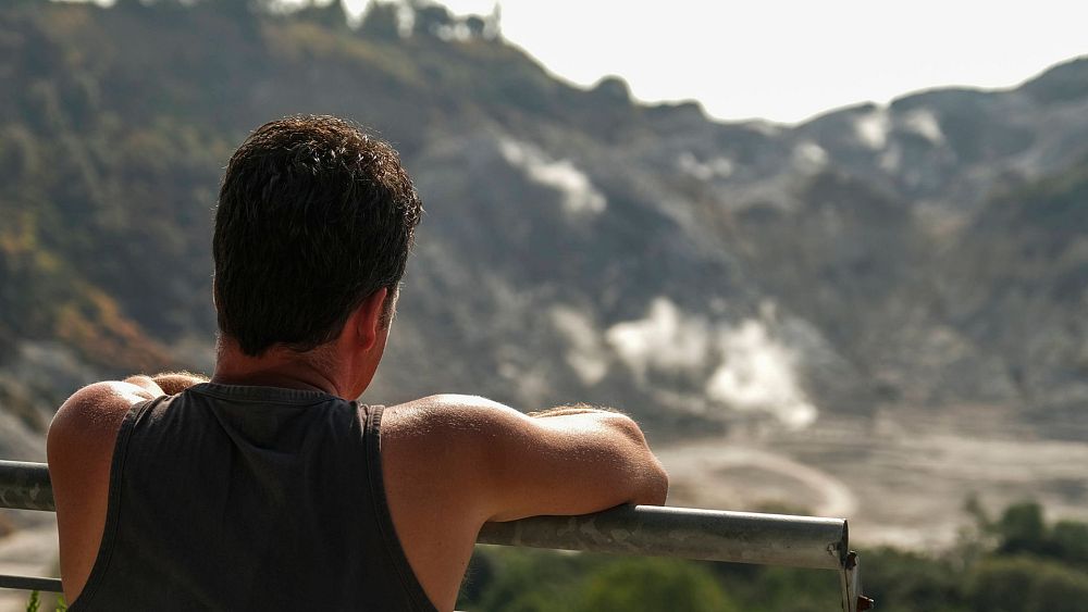Турист гледа към кратера на солфатара, един от четиридесетте вулкана,
