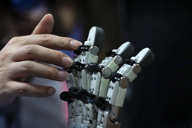 A visitor touches robotic fingers during the annual World Robot Conference near Beijing, August 2023