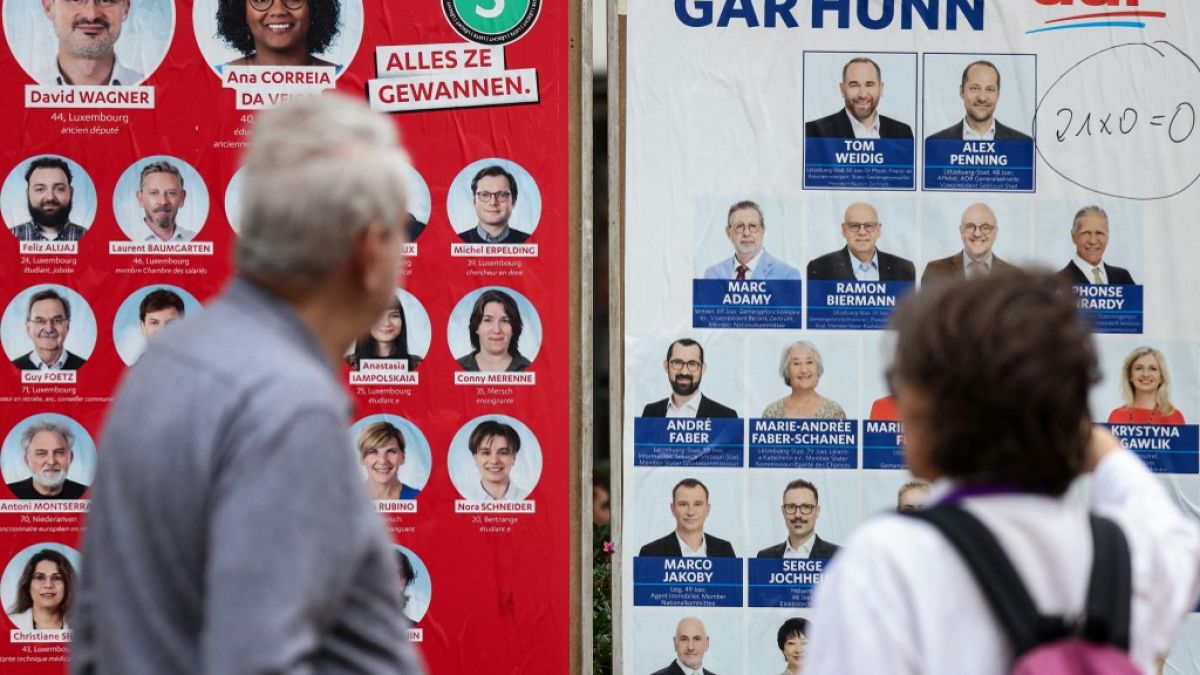 Luxemburgueses olham para cartazes eleitorais