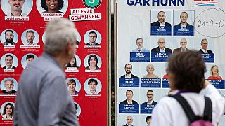Luxemburgueses olham para cartazes eleitorais