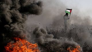 Palesztin zászlót lenget egy tüntető felgyújtott tárgyak sűrű füstjében a Gázai övezet keleti határán kitört zavargások alatt 2023. szeptember 22-én – képünk illusztráció