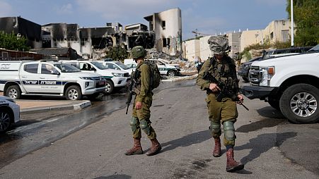 Israeli soldiers walk near the police station that was overrun by Hamas militants on Saturday