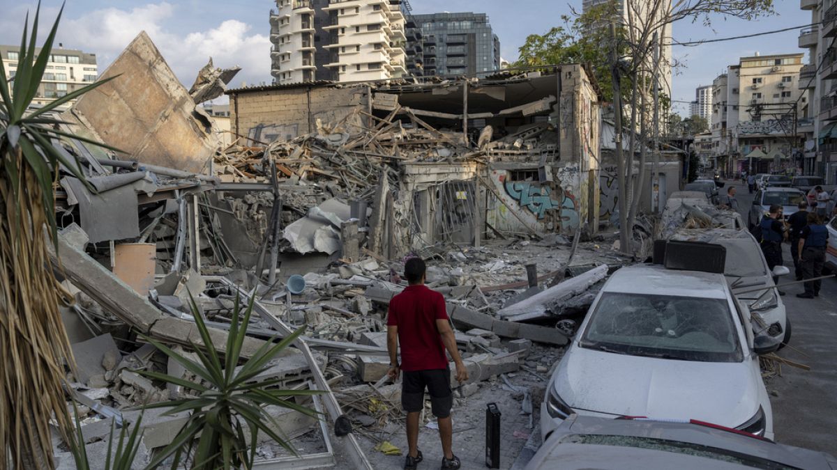 Des Israéliens inspectent les décombres d'un bâtiment après qu'il ait été touché par une roquette tirée depuis la bande de Gaza, à Tel Aviv, Israël, dimanche 8 octobre 2023.