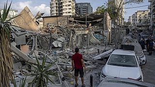 Des Israéliens inspectent les décombres d'un bâtiment après qu'il ait été touché par une roquette tirée depuis la bande de Gaza, à Tel Aviv, Israël, dimanche 8 octobre 2023.