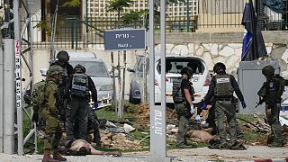 Izraeli katonák lelőtt terroristák holttestei mellett Szderotban
