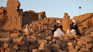 Men beside rubble of their destroyed homes after an earthquake in Zenda Jan district in Herat province, of western Afghanistan, Sunday, Oct. 8, 2023.