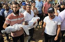 Palestinian man carries child killed in Israeli airstrike on Gaza, October 8th 2023