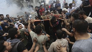 Спасатели, предположительно, палестинские, выносят пострадавшего из-под руин дома. 