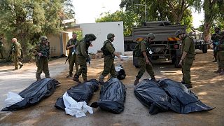 Israeli soldiers stand next to the bodies of Israelis killed by Hamas militants in kibbutz Kfar Azza on Tuesday