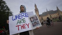 متظاهرة تحمل صوراً لمعتقلين اختفوا في سوريا أمام المحكمة الدولية