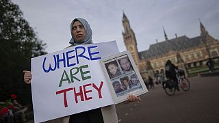 Eine Demonstrantin mit Bildern von Menschen, die ihrer Meinung nach in Syrien verschwunden sind, vor dem IGH in Den Haag