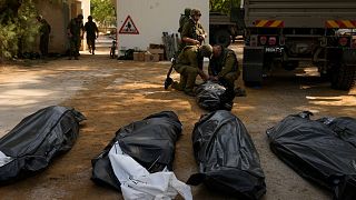 سربازان در کنار اجساد اسرائیلی‌هایی که روز سه‌شنبه توسط شبه‌نظامیان حماس در کیبوتص «کفار عزه» کشته شدند، ایستاده‌اند.