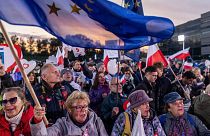 People wave Polish and EU flags as they gather outside a tv studio where main candidates in the upcoming Polish elections are taking part in a debate in Warsaw, Poland.